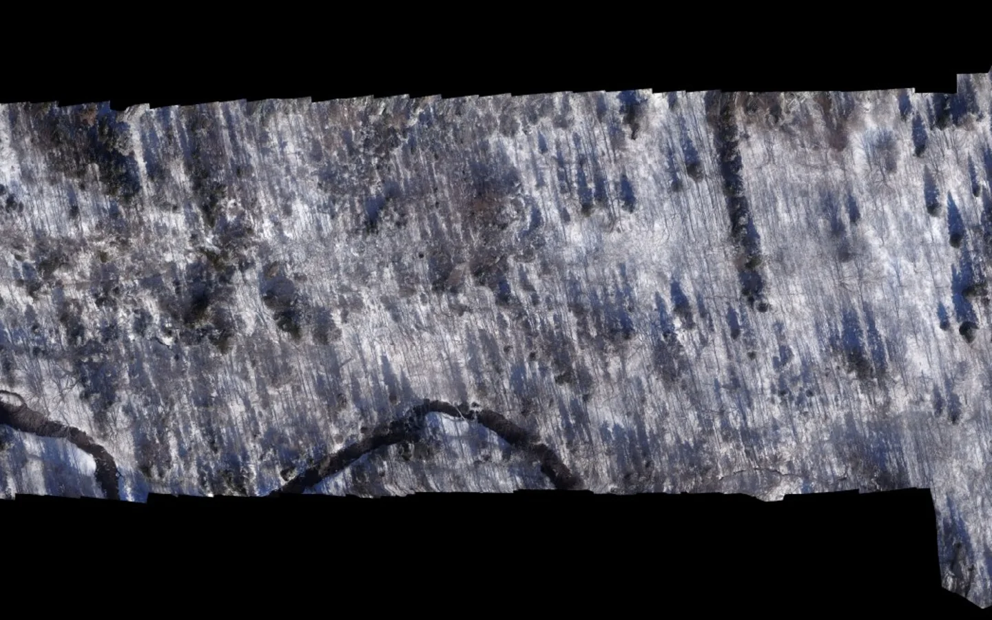 Cropped winter aerial mosaic showing a winding stream through snow-covered forest, with visible seams between the creator's source photographs.